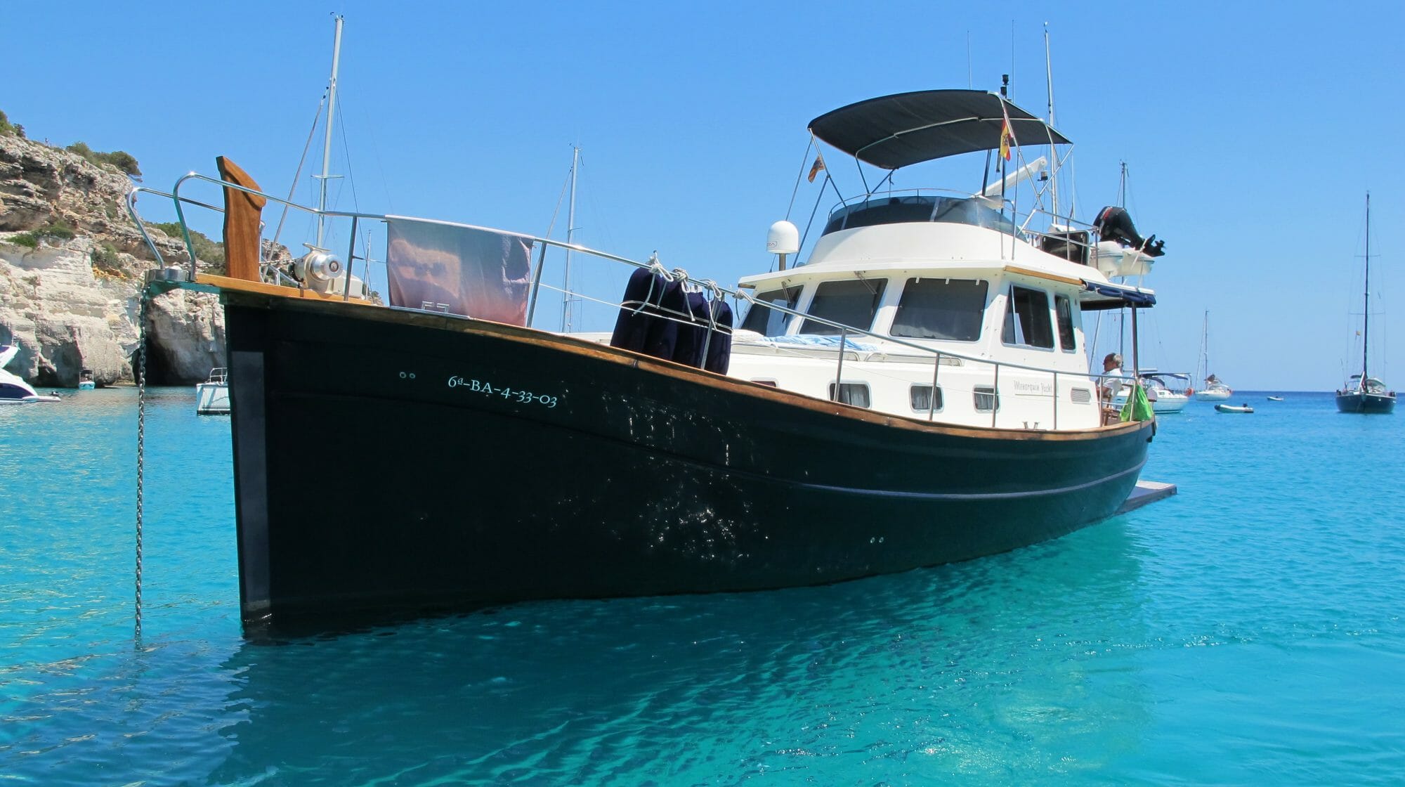 Llaüt, embarcación típica de Menorca, en una cala de mar azul
